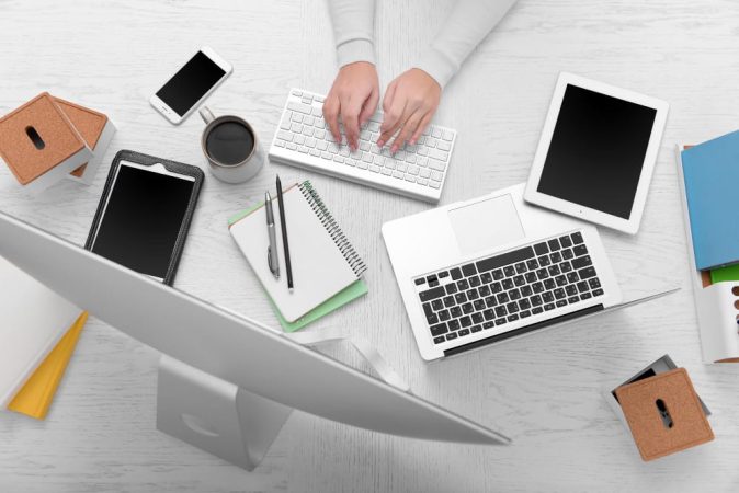 Vue de dessus de mains tapant sur un clavier pour télécharger un kbis extrait gratuit sur un espace de travail connecté