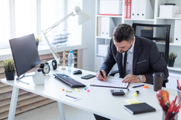 Un entrepreneur en costume à son bureau étudie un document administratif pour obtenir son kbis extrait gratuit